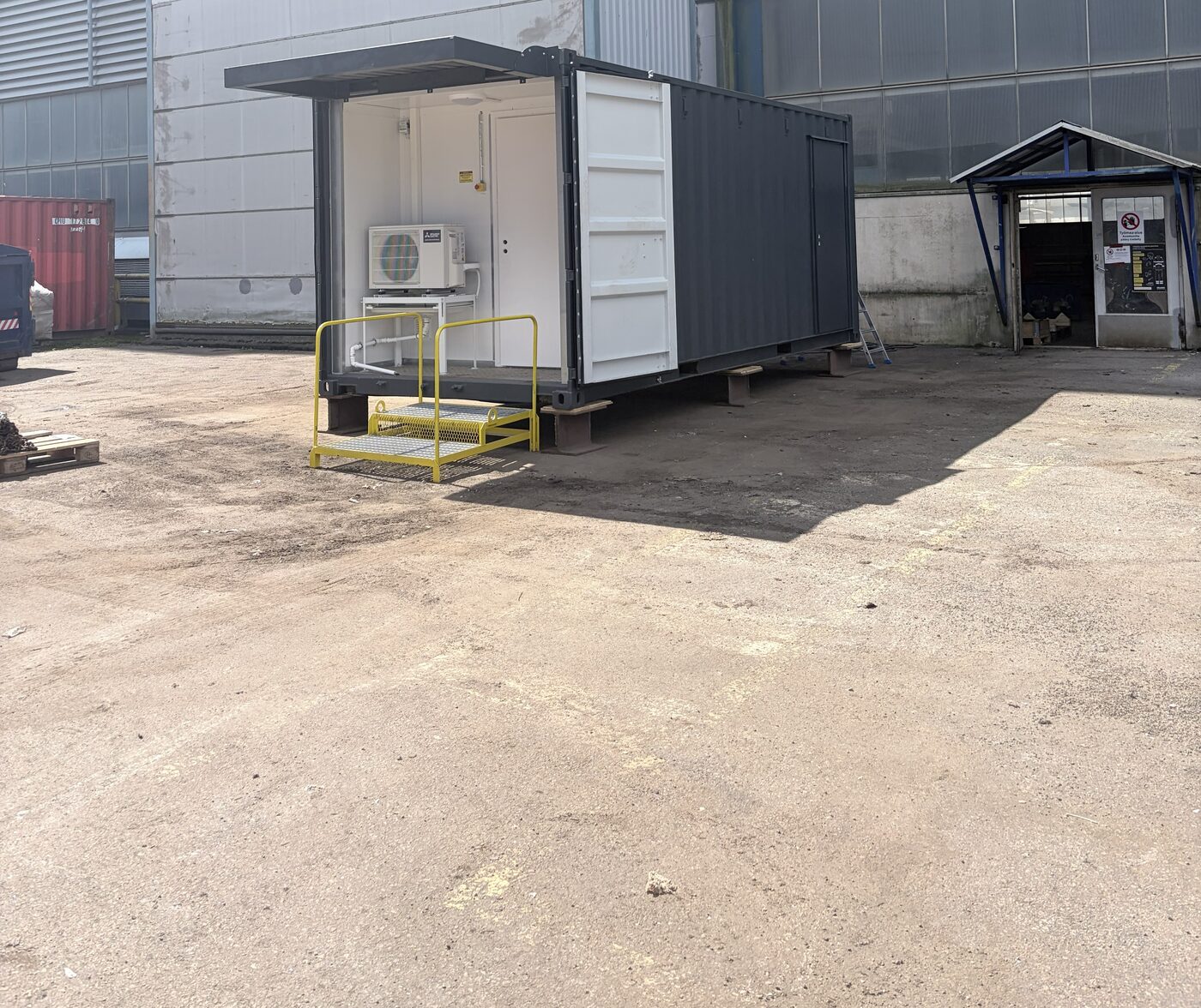 Delivered equipment container on site with covered entrance and access platform