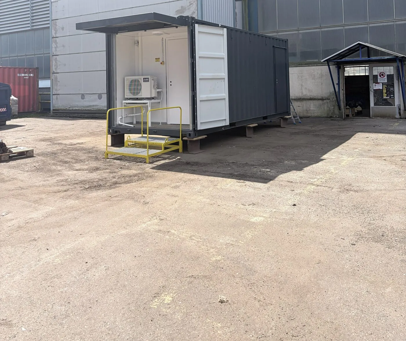 Delivered equipment container on site with covered entrance and access platform